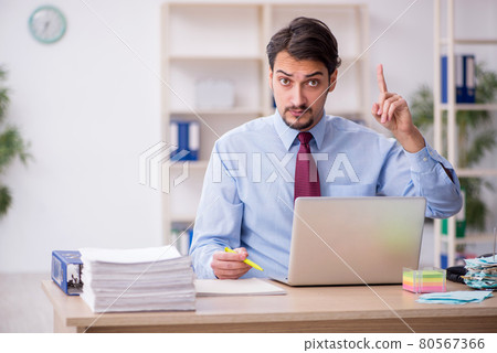 Young male employee and too much work in the office Young male employee and too much work in the office 80567366