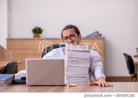 Young male employee unhappy with excessive work in the office Young male employee unhappy with excessive work in the office 80569180