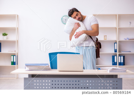 Young male employee coming to work straight from bed Young male employee coming to work straight from bed 80569184