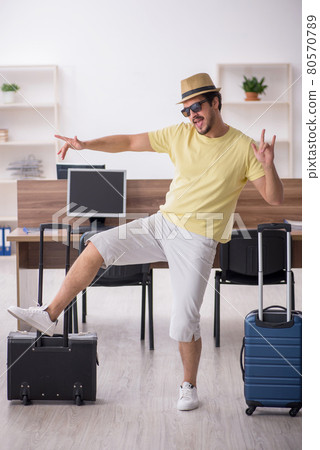 Young male employee preparing for trip at workplace 80570789
