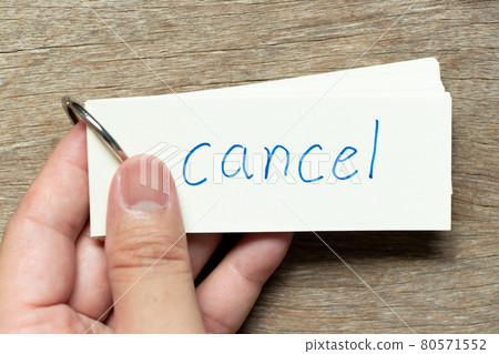 Man hold the flash card with handwriting word cancel on wood background 80571552