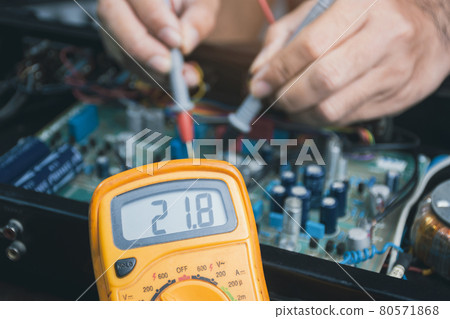 Electrician checking voltage of electronic circuit board with digital multimeter Electrician checking voltage of electronic circuit board with digital multimeter 80571868