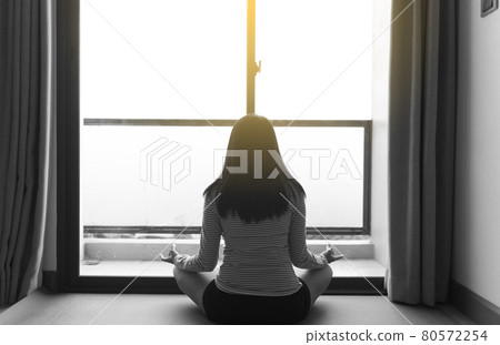 Back view of hand woman practices yoga and meditation on the lotus posture in bedroom after raining Back view of hand woman practices yoga and meditation on the lotus posture in bedroom after raining 80572254