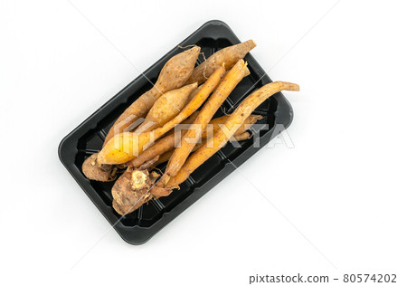 Close up fresh finger roots or galingale in the plastic black tray on white background. Top view image of herb plant Finger Root or Krachai in Thailand language. 80574202