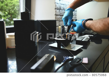 Professional hair dyeing concepts in beauty salon. Close-up of hairdresser hands pouring a liquid color pigment from a tube into a bowl 80575068