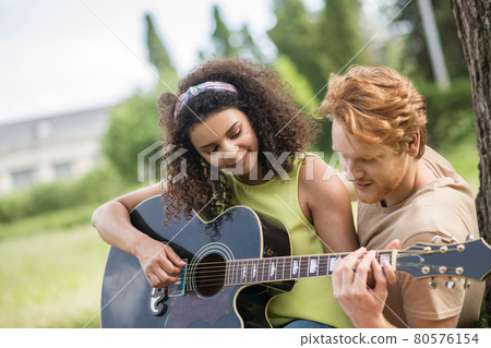 Guy teaching his girlfriend to play guitar Guy teaching his girlfriend to play guitar 80576154