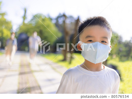Happy little boy wearing medical mask walking park Happy little boy wearing medical mask walking park 80576534