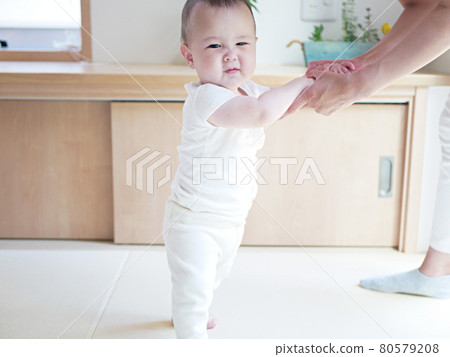 Half-baby holding her mother's hand and standing Half-baby holding her mother's hand and standing 80579208