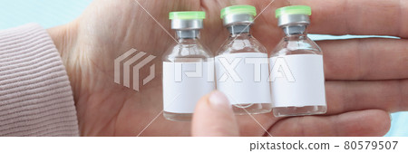 Holding three vials of coronavirus vaccine of choice in hand 80579507