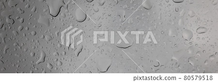 Raindrops on glass against gray sky closeup Raindrops on glass against gray sky closeup 80579518