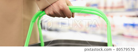 Female hand holds grocery basket on background of store 80579570