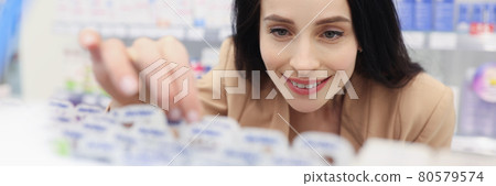 Woman in cosmetics store picks up skin care product Woman in cosmetics store picks up skin care product 80579574