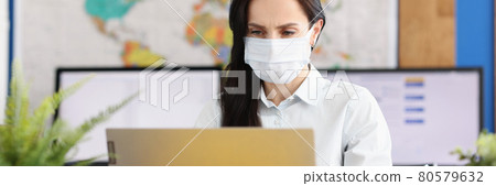 Woman in protective medical mask works at laptop 80579632