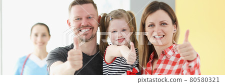 Smiling family doing thumbs up gesture in background is doctor 80580321