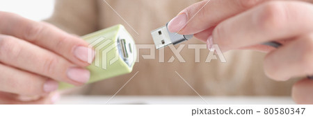 Woman hand inserts usb wire from smartphone into USB flash drive Woman hand inserts usb wire from smartphone into USB flash drive 80580347