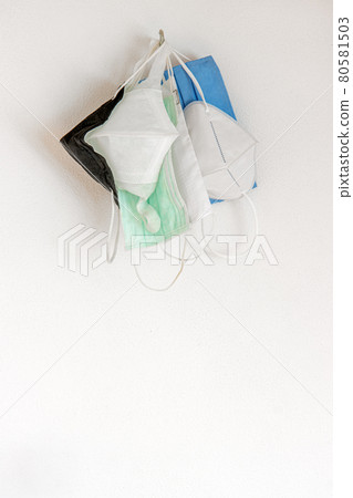 The used protective face masks hanging on a hook on a white wall, close up view The used protective face masks hanging on a hook on a white wall, close up view 80581503