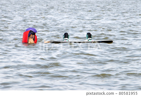 A child swims in the water with a surfboard 80581955