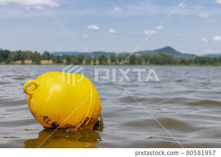 A yellow buoy is floats on a surface of water in a lake. A yellow buoy is floats on a surface of water in a lake. 80581957