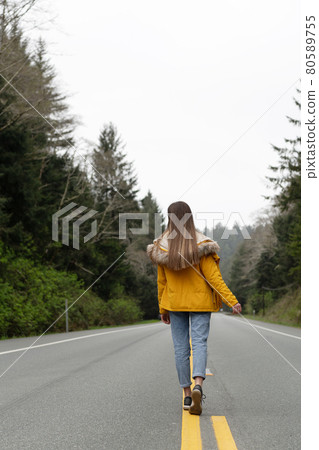 hitchhiker girl back view in coat walking on highway, travel hitchhiker girl back view in coat walking on highway, travel 80589755