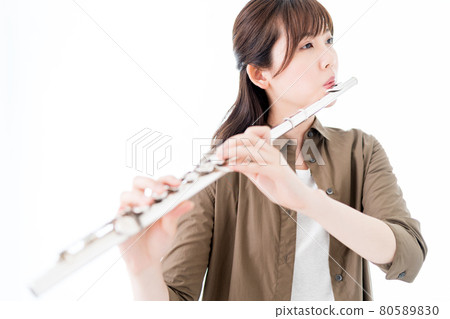 A woman playing the flute in a casual outfit 80589830