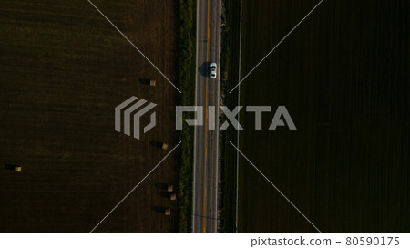 A bird's-eye view of an empty road, which is located next to the field. A bird's-eye view of an empty road, which is located next to the field. 80590175