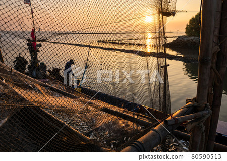 fisherman with fish on boat at dock during sunset fisherman with fish on boat at dock during sunset 80590513