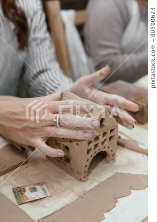 Women's hands knead clay, drawing elements of the product. Production of ceramic products at the master class on ceramics. 80590623