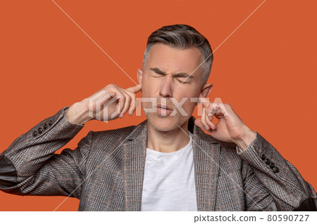Man with drooping eyelids covering ears with fingers Man with drooping eyelids covering ears with fingers 80590727