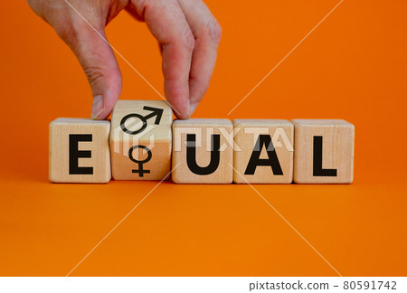 Gender eduality symbol. Male hand turns wooden cube with male and female symbol. Equal word. Business and gender equality concept. Beautiful orange background, copy space. 80591742