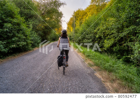 Adventurous White Cacasusian Woman riding a bicycle on a road. 80592477