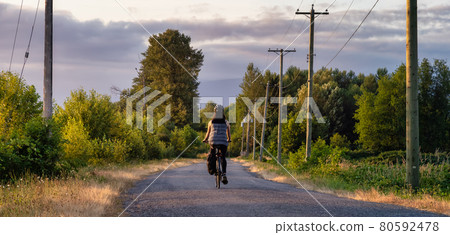 Adventurous White Cacasusian Woman riding a bicycle on a road. 80592478