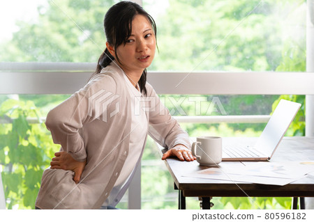 A woman who has a backache during work A woman who has a backache during work 80596182