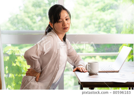 A woman who has a backache during work A woman who has a backache during work 80596183
