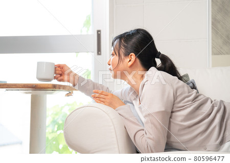 A woman relaxing on the sofa with coffee A woman relaxing on the sofa with coffee 80596477