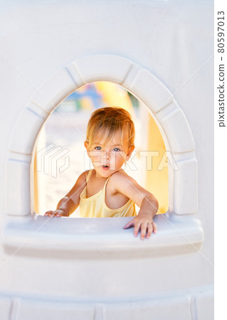 Little girl sitting outside the window of a toy castle Little girl sitting outside the window of a toy castle 80597013