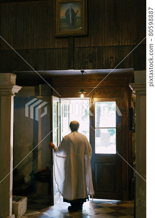 Priest opens the doors of the church. Back view 80598887