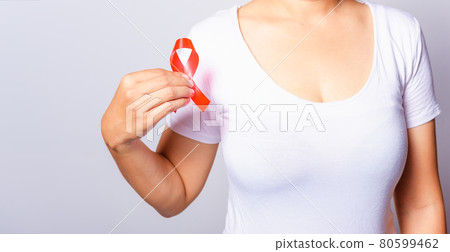 Closeup of female with red ribbon HIV AIDS on hand 80599462