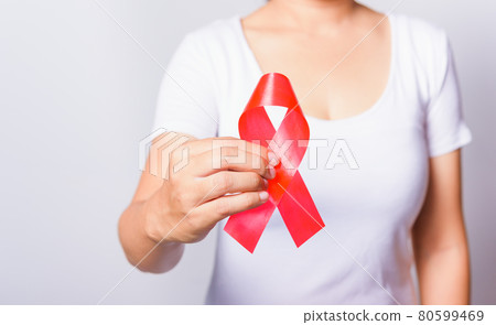 Closeup of female with red ribbon HIV AIDS on hand 80599469