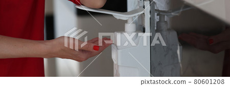 Woman hand pushes pump head onto bottle of gel, soap or hand sanitizer and holds drops of gel in her hand Woman hand pushes pump head onto bottle of gel, soap or hand sanitizer and holds drops of gel in her hand 80601208