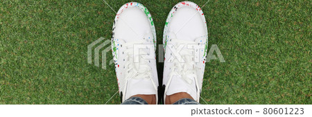 Women legs in blue jeans and white beautiful sneakers on green lawn. 80601223