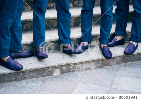 Seven groom's best men in identical blue trousers and shoes stand on the stairs, close-up  80601941