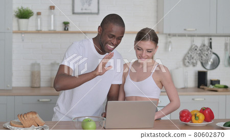 Mixed Race Couple Talking on Video Call in Kitchen 80602870