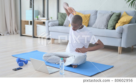 African Man doing Video Call on Laptop while on Yoga Mat African Man doing Video Call on Laptop while on Yoga Mat 80602956