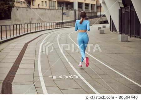 Beautiful fit caucasian woman is doing exercises outdoors at the city 80604440