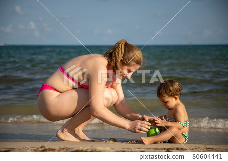 mothers Day. mom and baby enthusiastically play in the sand on the seashore 80604441