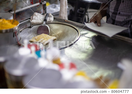 process for the preparation of tasty traditional Thai pancakes on a street counter. male hands fry a pancake in oil. local specialty process for the preparation of tasty traditional Thai pancakes on a street counter. male hands fry a pancake in oil. local specialty 80604777