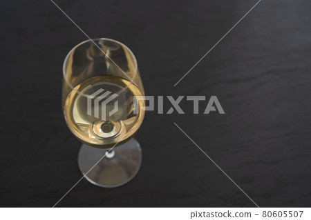 White wine in a wineglass on black oak table with copy space 80605507
