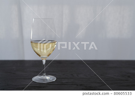 White wine in a wineglass on black oak table with copy space 80605533