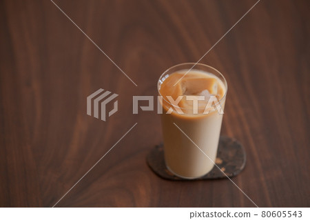 Ice coffee wih milk in tumbler glass on black walnut table Ice coffee wih milk in tumbler glass on black walnut table 80605543