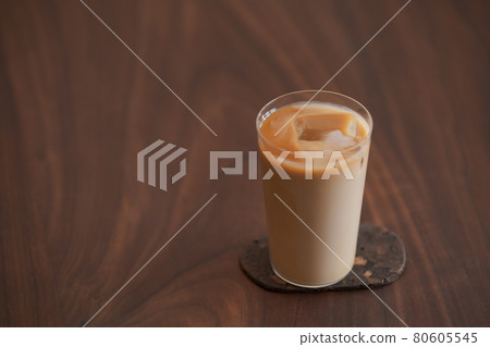 Ice coffee wih milk in tumbler glass on black walnut table 80605545
